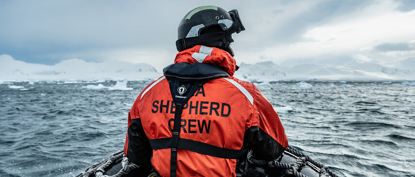 A man with a red Sea Shepherd crew jacket on a boat at sea